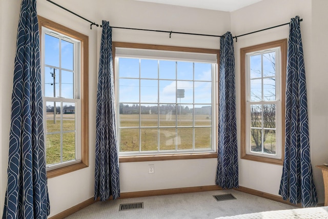 carpeted spare room featuring baseboards and visible vents