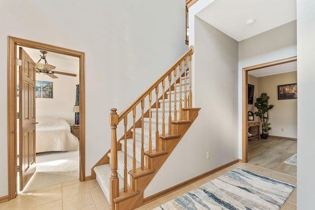 stairs with tile patterned floors, ceiling fan, and baseboards