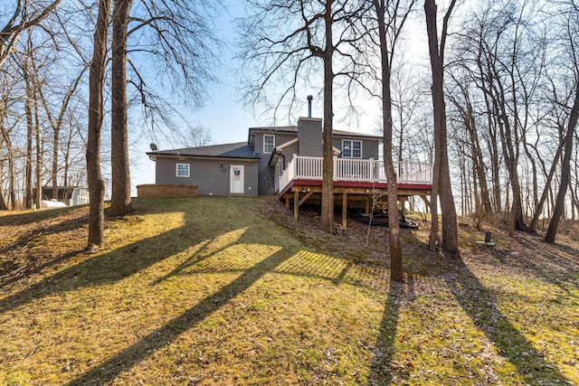 back of house with a deck, a lawn, and a chimney