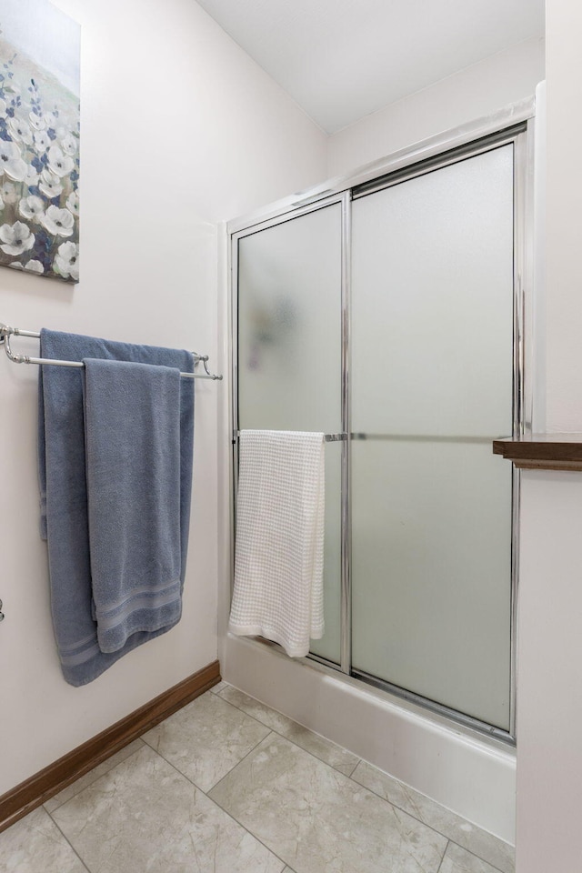 bathroom featuring tile patterned floors, baseboards, and enclosed tub / shower combo