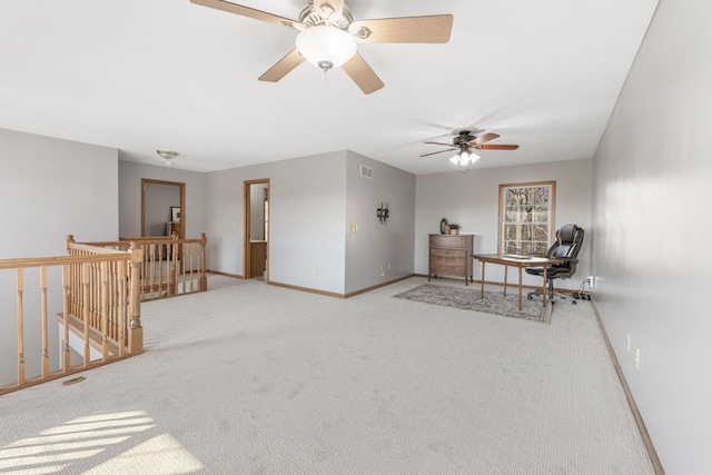 living area with carpet, visible vents, baseboards, ceiling fan, and an upstairs landing