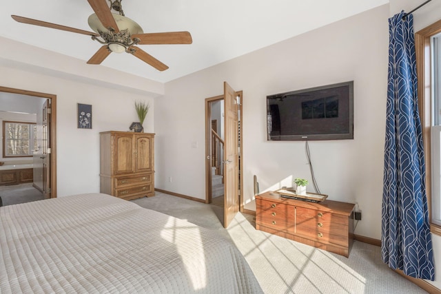 bedroom featuring a ceiling fan, baseboards, light colored carpet, and ensuite bathroom