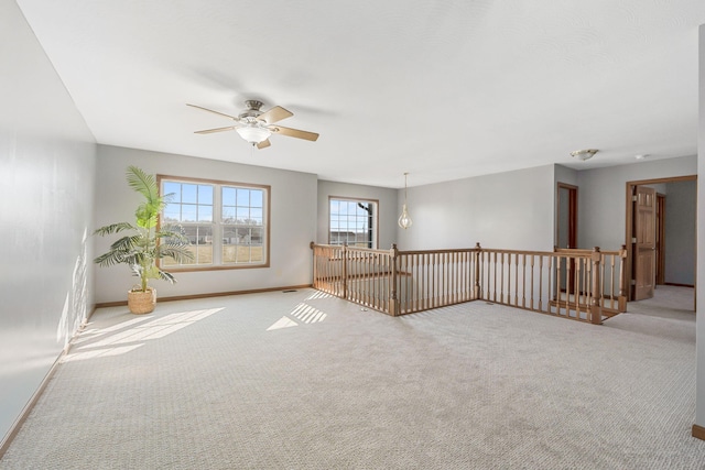 carpeted spare room featuring baseboards and ceiling fan