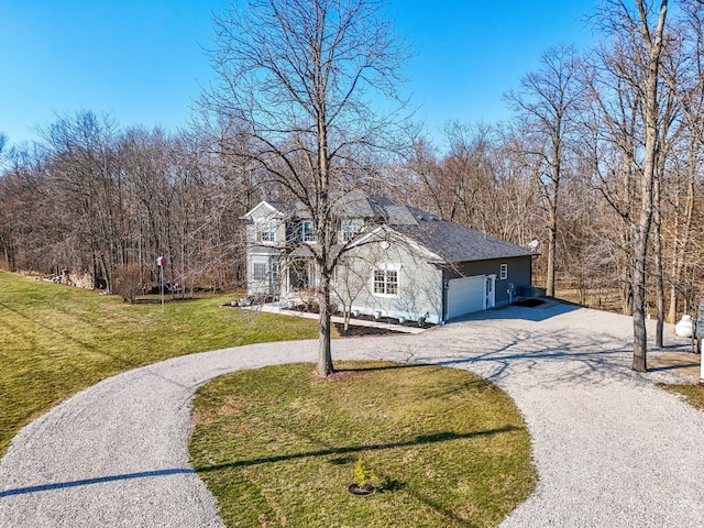 view of front facade featuring curved driveway, an attached garage, and a front yard