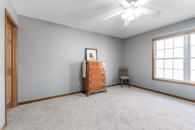 unfurnished bedroom with light colored carpet, a ceiling fan, and baseboards