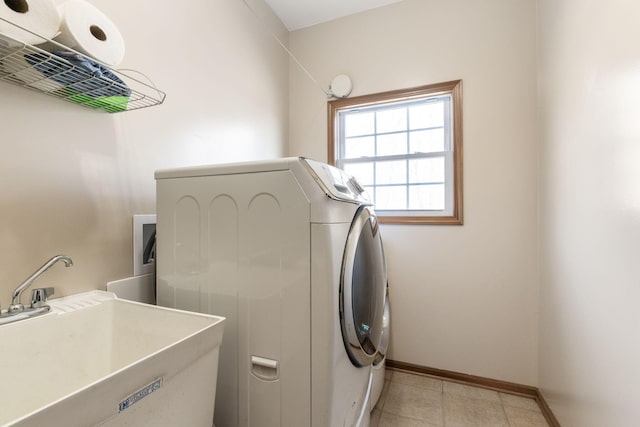 clothes washing area featuring baseboards, laundry area, light tile patterned flooring, a sink, and washer and dryer