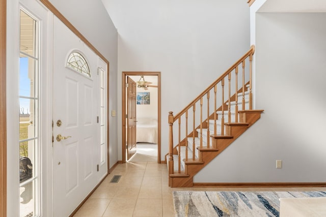 tiled entrance foyer with visible vents, stairway, a ceiling fan, and baseboards