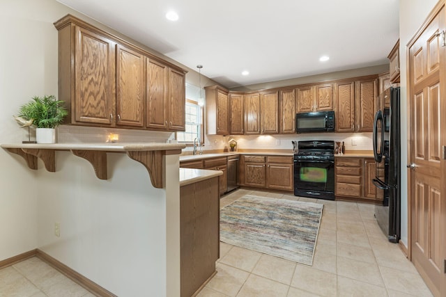 kitchen with tasteful backsplash, brown cabinets, a peninsula, and black appliances