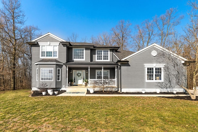 traditional-style house featuring covered porch, a shingled roof, and a front yard