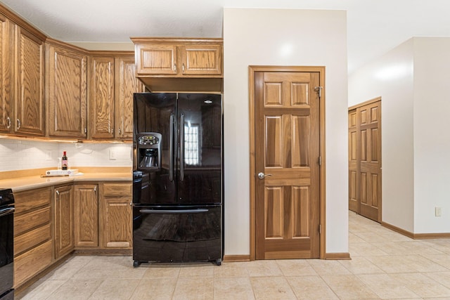 kitchen featuring black fridge, tasteful backsplash, baseboards, light countertops, and range