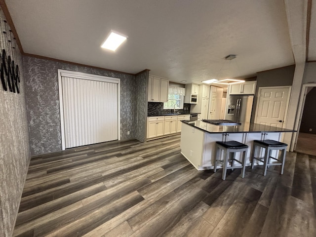 kitchen featuring stainless steel appliances, dark countertops, dark wood-style flooring, and wallpapered walls