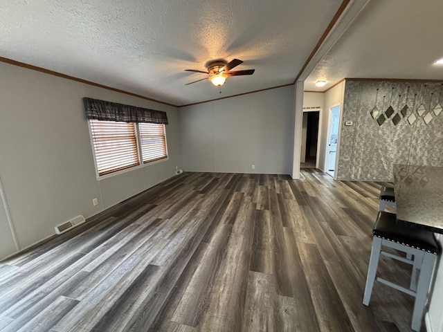 unfurnished living room with dark wood-style flooring, crown molding, visible vents, a ceiling fan, and a textured ceiling