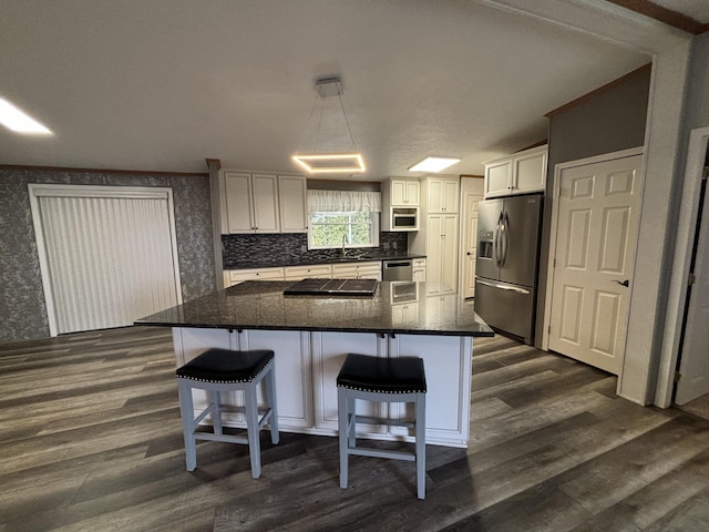 kitchen with stainless steel appliances, dark wood-style flooring, a sink, white cabinets, and wallpapered walls