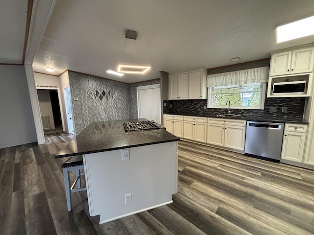 kitchen with a sink, dark countertops, dark wood finished floors, and dishwasher