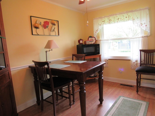 dining room with crown molding, wood finished floors, ceiling fan, and baseboards