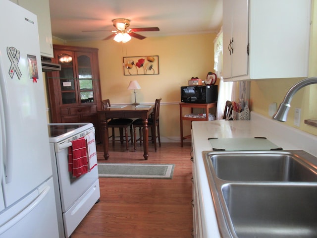 kitchen with white appliances, a sink, wood finished floors, ceiling fan, and under cabinet range hood