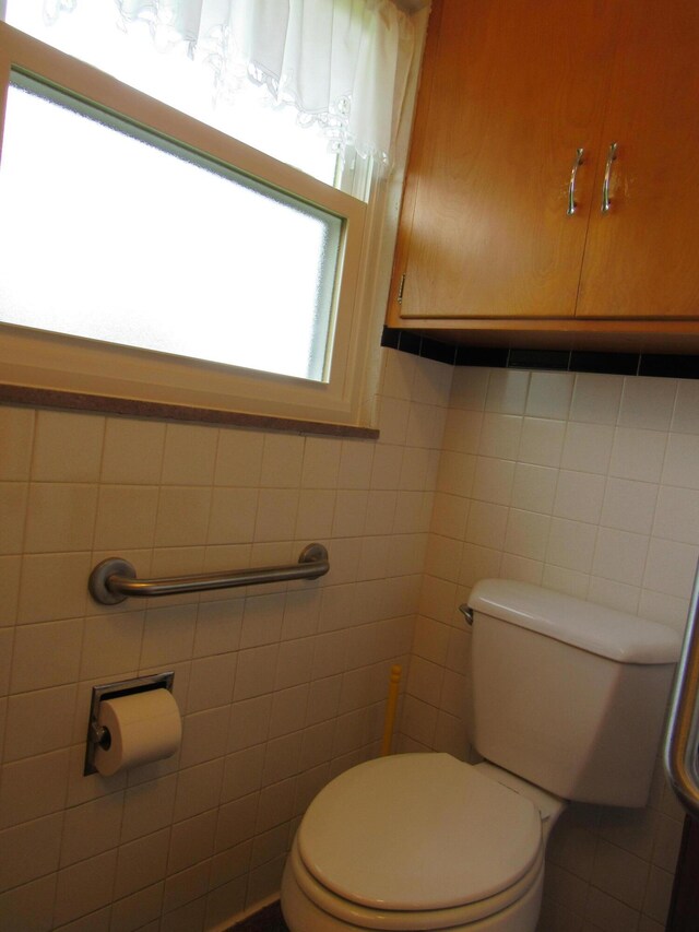 half bathroom with toilet and tile walls