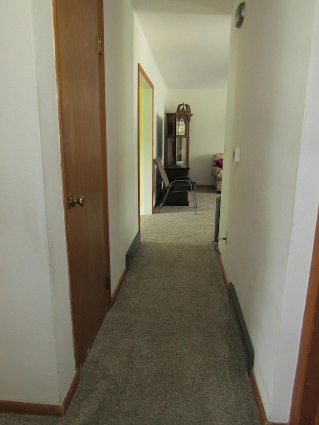 hallway featuring carpet and baseboards