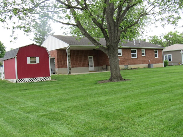 rear view of property with brick siding, a storage unit, a yard, and an outbuilding
