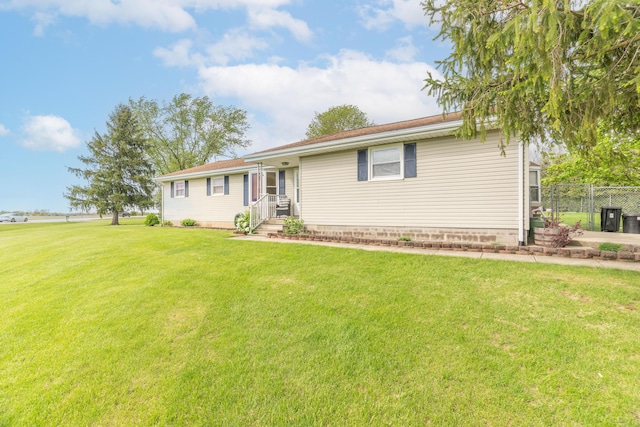 ranch-style home featuring fence and a front lawn