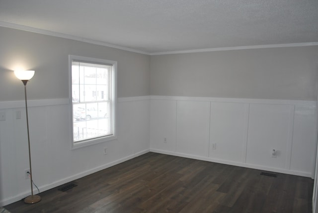 spare room with ornamental molding, dark wood-type flooring, wainscoting, and visible vents