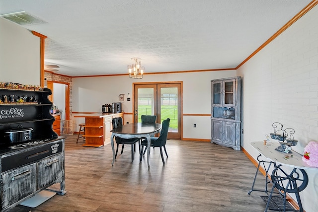 dining room with a textured ceiling, a chandelier, ornamental molding, visible vents, and dark wood-style floors