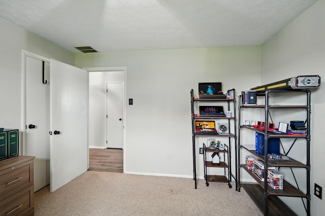 interior space featuring visible vents, a textured ceiling, and baseboards