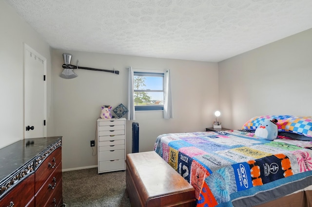 bedroom with baseboards, a textured ceiling, and dark carpet