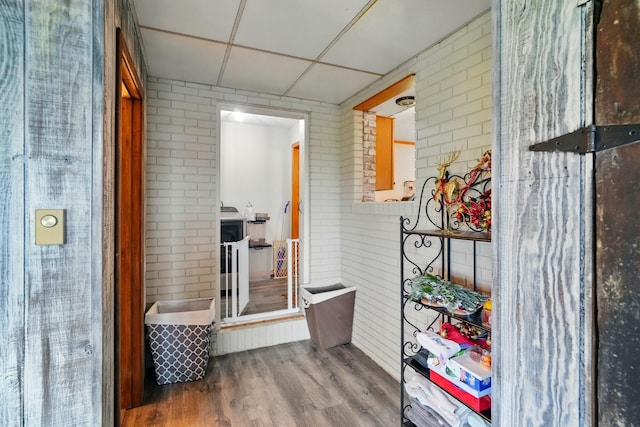 hall with wood finished floors and brick wall