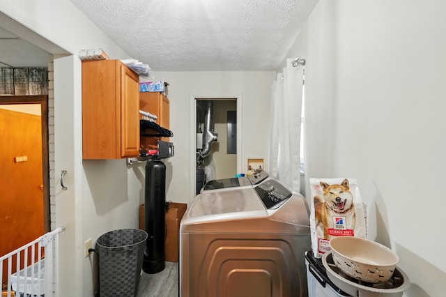 washroom featuring washer and dryer, a textured ceiling, wood finished floors, and cabinet space