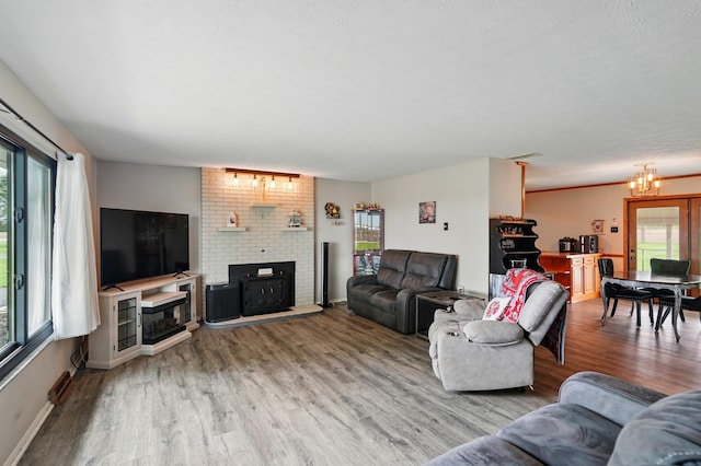 living room with baseboards, a brick fireplace, wood finished floors, and a chandelier