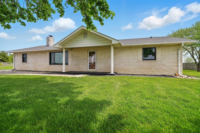 ranch-style home with brick siding, a front lawn, fence, and a chimney