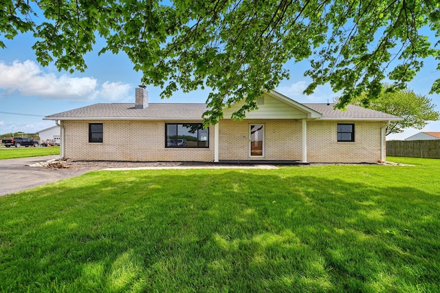 view of front of property featuring brick siding, a front lawn, fence, and a chimney