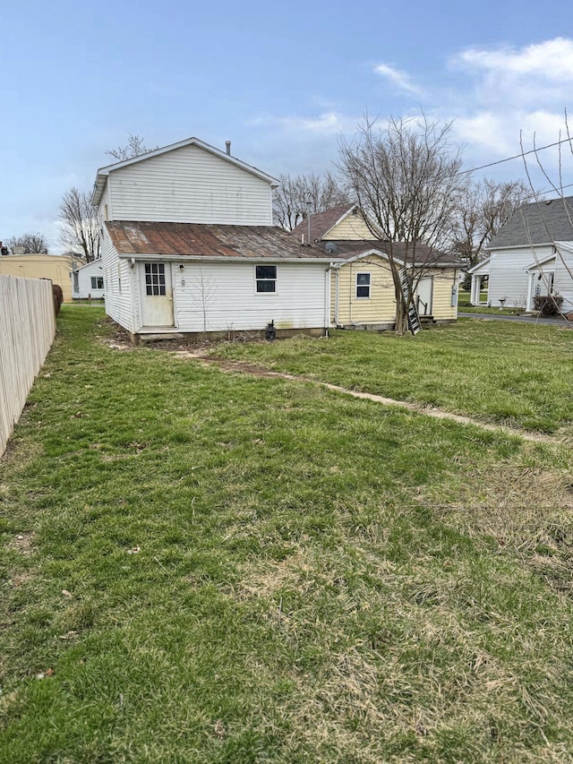 rear view of property with a lawn and fence