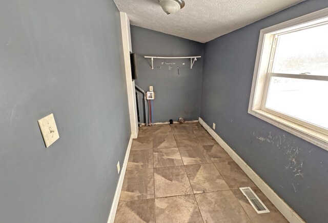 washroom with baseboards, visible vents, and a textured ceiling
