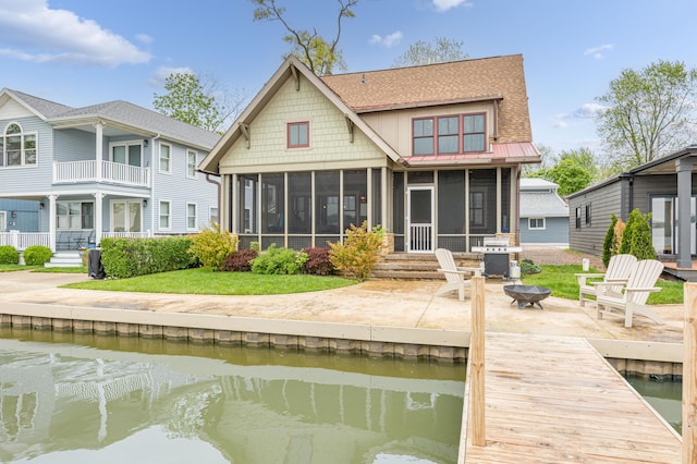 7933 Hickory Ave, Russells Point, OH 43348 - rear view of property featuring a sunroom, an outdoor fire pit, a patio area, a water view, and a shingled roof