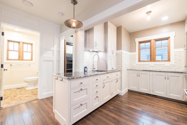 7933 Hickory Ave, Russells Point, OH 43348 - kitchen featuring a sink, dark wood-type flooring, white cabinets, light stone counters, and a peninsula