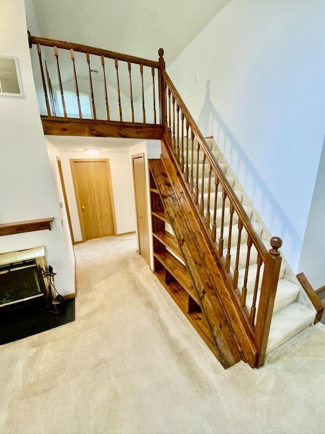 224 Oakcrest Ct, Russells Point, OH 43348 - stairs featuring carpet, a high ceiling, a glass covered fireplace, and baseboards