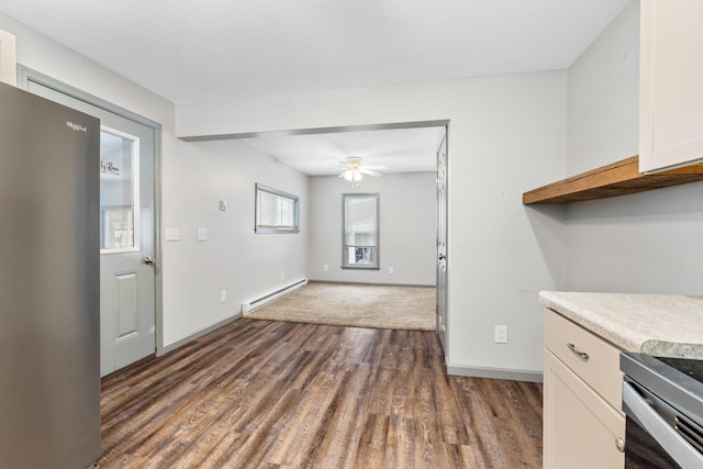 kitchen with dark wood-style floors, stainless steel appliances, light countertops, white cabinets, and baseboard heating