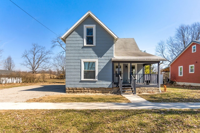 view of front of property with covered porch, a shingled roof, and a front lawn