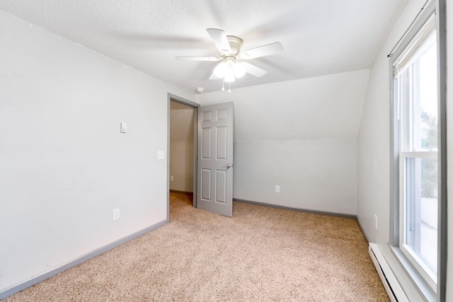 unfurnished room with carpet floors, a baseboard radiator, baseboards, ceiling fan, and vaulted ceiling