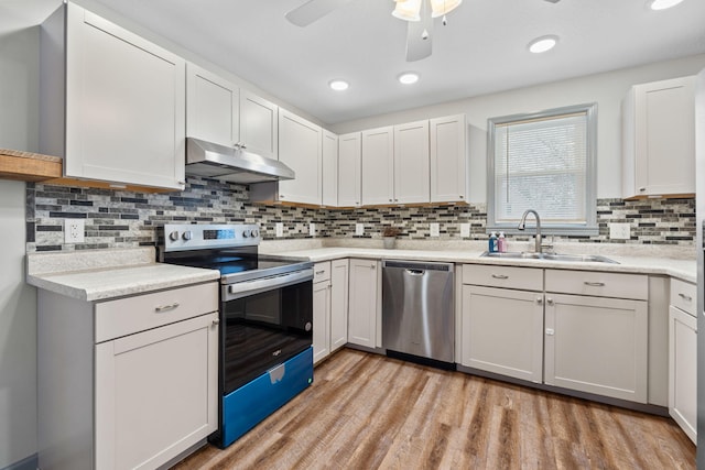 kitchen featuring light wood-type flooring, under cabinet range hood, a sink, appliances with stainless steel finishes, and light countertops