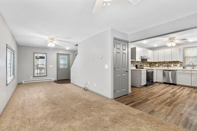 kitchen with under cabinet range hood, a baseboard heating unit, stainless steel appliances, light countertops, and decorative backsplash