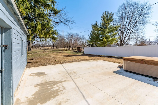 view of patio / terrace with an outbuilding, a fenced backyard, and a hot tub