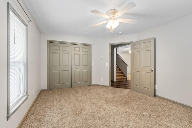 unfurnished bedroom featuring a closet, ceiling fan, baseboards, and carpet floors