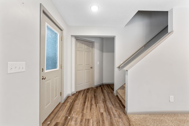 entrance foyer with stairs, wood finished floors, and baseboards