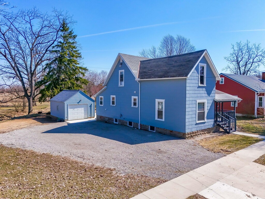 210 N Main St, West Mansfield, OH 43358 - view of side of home with a garage, gravel driveway, an outdoor structure, and a shingled roof