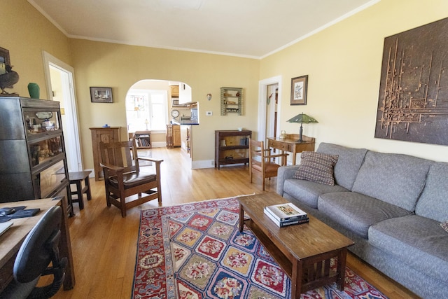 living room with arched walkways, light wood-style floors, and crown molding