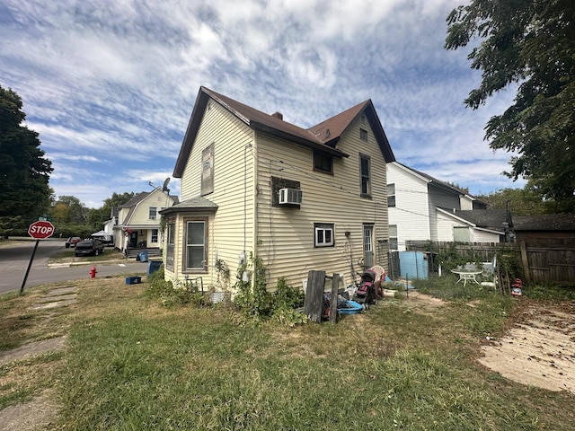 view of side of property featuring a wall unit AC and a lawn