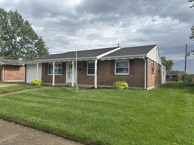 ranch-style house featuring an attached garage, brick siding, driveway, a front yard, and a shingled roof